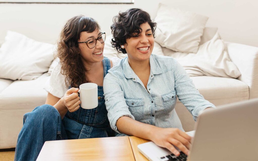 Women looking at computer together on the floor