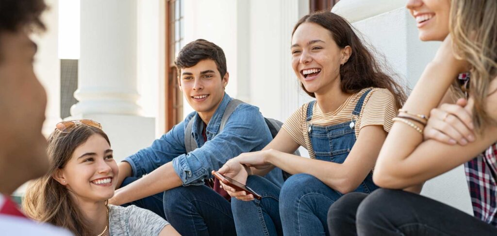 group of teenagers sitting on stairs smiling